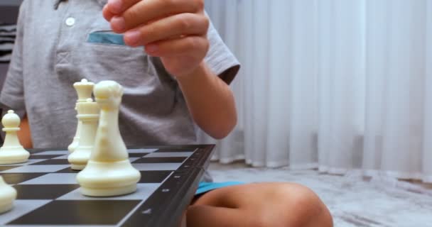 グレーのティーを着た少年がチェスをする 閉鎖だ チェスボードのレベルで撮影 — ストック動画