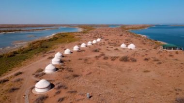 Güneşli bir yaz gününde Aydarkul Gölü kıyısındaki yurtlar üzerinde İHA uçuşu