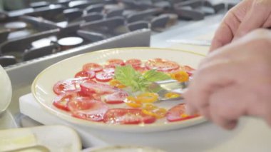 Şef yavaş çekimde doğranmış domatesleri yakın çekimde servis eder.