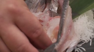 Daikon ile suşi süslemesi yapmak, yapraklar ve kafayla balık kesmek ve siyah kare tabakta balık dilimleri. Yakın çekim.