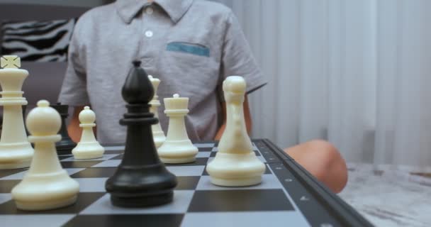 グレーのティーを着た少年がチェスをする 閉鎖だ チェス盤のレベルで撮影 カムが去った — ストック動画