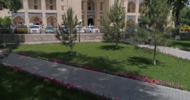 Buhara 'nın Lyab-i Hauz mimari topluluğu. Drone yeşil kareden havalanıyor, drone meydandan kalkıyor, caddenin üzerinden uçuyor, Kukeldash 'ı vuruyor. Sonra yükselir.