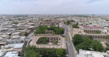 İnsanlar Buhara 'daki Lyab-i Hauz mimari topluluğu Khanaka Nadir Divan-Beghi' ye giriyor. İnsansız hava aracı kamerası, mozaikle döşenmiş ön kemer boyunca iniyor. Bulutlu bir günde çekilmiş..