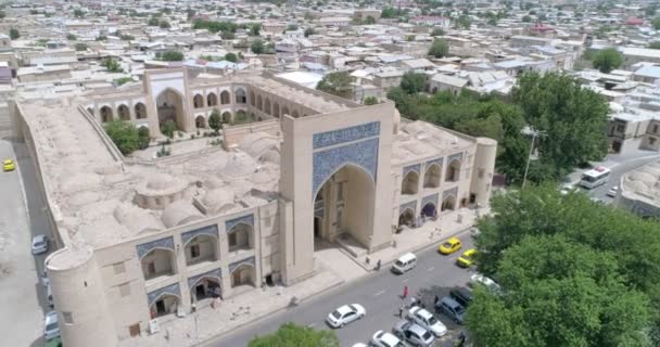 人们进入了Lyab Hauz建筑合奏的Khanaka Nadir Divan Beghi Bukhara 无人机凸轮沿着正面华丽的镶嵌形拱门下降 在阴天拍摄 — 图库视频影像