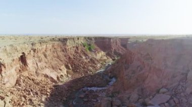 Çöldeki vadide akan nehir. Koyun sürüsü sulama yerine geldi. İnsansız hava aracı, hava görüntüsü