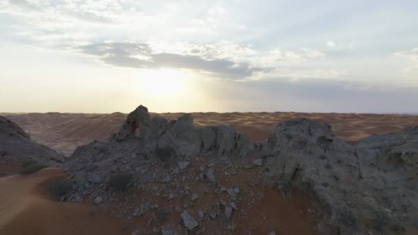 在落日的天空中 一架无人驾驶飞机在沙质沙漠中的一块漏水的岩石上盘旋 — 图库视频影像