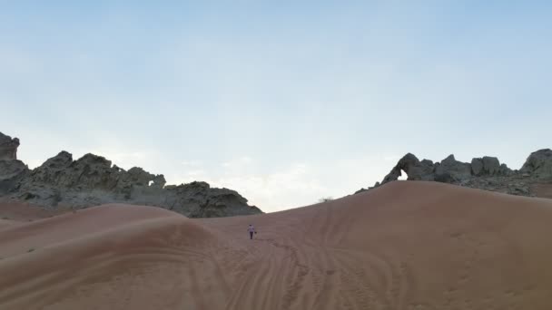 Беспилотник Стреляет Человека Поднимающегося Песчаной Дюне Скале Фоне Закатного Неба — стоковое видео