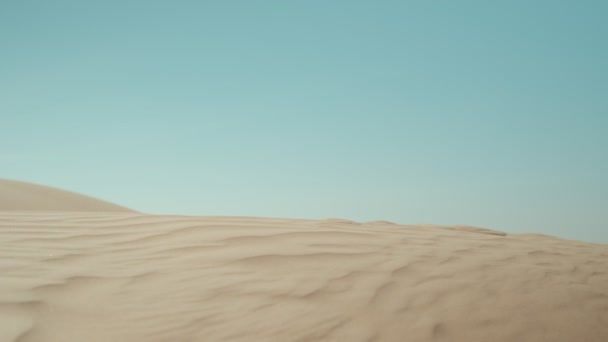 銀のビキニの若いセクシーな女性が空に対して砂漠の砂の上を裸足で歩く — ストック動画