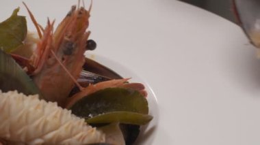 Daikon, limon dilimleri, yapraklar, kafayla kesilmiş balık ve siyah kare tabakta farklı türde kırmızı balık dilimleri ile suşi süslemek. Yakın çekim.