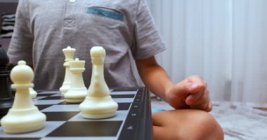 Gri tişört giyen çocuk satranç dönüşünü yapıyor. - Yakın çekim. Satranç tahtası seviyesinde çekildi. Cam sola hareket ediyor