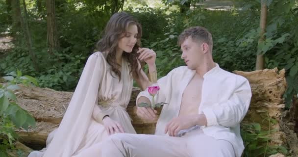 Pair Young Lovers Light White Robes Sit Log Garden Flowering — Vídeo de Stock
