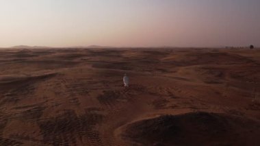 İnsansız hava aracı, kanat çırpan beyaz cüppeli ve türbanlı zayıf bir Arap 'ı çölde gün batımına doğru yalınayak yürürken vurur..