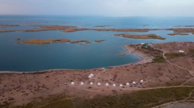 Güneşli bir yaz gününde Aydarkul Gölü kıyısındaki yurtlar üzerinde İHA uçuşu