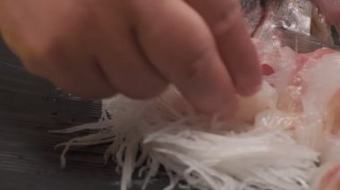 Daikon ile suşi süslemesi yapmak, yapraklar ve kafayla balık kesmek ve siyah kare tabakta balık dilimleri. Yakın çekim.