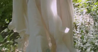 A young girl runs through a summer flowering garden among the trees in a light white fluttering dress. Slow motion