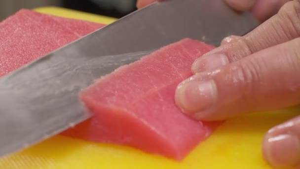 シェフは赤魚をナイフで黄色のボード上のスライスにカットします — ストック動画