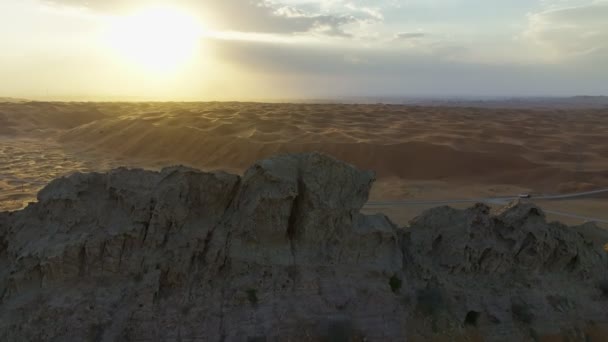 在落日的背景下 一架无人驾驶飞机在沙质沙漠中的岩石山脊上飞行 — 图库视频影像