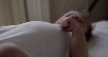 Beyaz bedenli yeni doğmuş erkek bebek beyaz çarşafın üzerinde yatıyor. Kapalı çekim, yakın çekim.