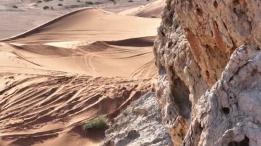 Şamanlar gibi giyinmiş bir adam elinde asayla çölün kumlarında yürüyor. İnsansız hava aracı