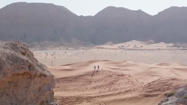 無人機は アラブ首長国連邦の砂漠の砂の上に立つ数人の周りを飛行します — ストック動画