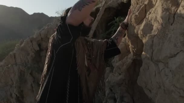 Een Jonge Man Met Baard Sjamanenkleding Klimt Midden Woestijn Verenigde — Stockvideo