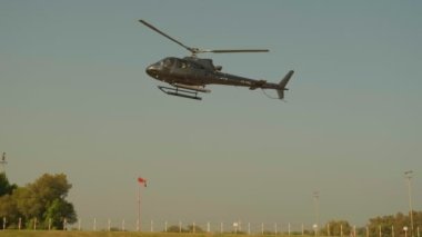 Mavi gökyüzüne karşı küçük özel bir helikopter Dubai 'deki bir havaalanına inmeye hazırlanıyor. Yavaş çekim.