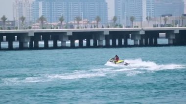 Açık denizlerde jet ski üzerinde can yeleği giymiş esmer bir kadın. Yavaş çekim