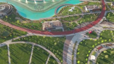 Parkta güneşli bir günde insansız hava aracının uçuşu. İşleyen güzel bir çeşme, park inşaat halindeki otel ve evlerle çevrilidir. Hava görünümü