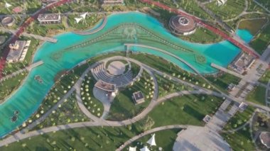 Parkta güneşli bir günde insansız hava aracının uçuşu. İşleyen güzel bir çeşme, park inşaat halindeki otel ve evlerle çevrilidir. Hava görünümü