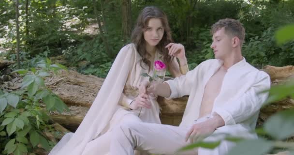 Pair Young Lovers Light White Robes Sit Log Garden Flowering — Wideo stockowe