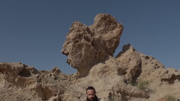 Young Bearded Shaman Stands Sand Dunes Rocks Clear Sky Slow — Stock Video