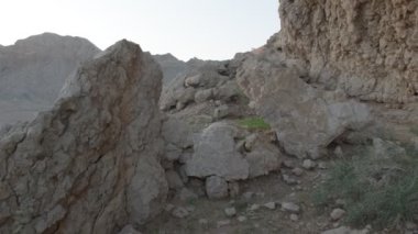 Gün batımının arka planına karşı çölün kum tepeleri arasında bir dağ sırası. Ağır çekim, BAE