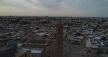 Şafak vakti Buhara 'daki ünlü Kalyan Poi Kalon Kompleksi ve Poi Kalon Minaret, Poi Kalan veya Po-i-Kalyan anıtında bir İHA uçar. Hava manzarası, Özbekistan