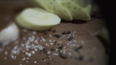 Doğranmış kabak, sarımsak, otlar ve tuz serpiştirilmiş tahtalar. Kapat, Yavaş Hareket