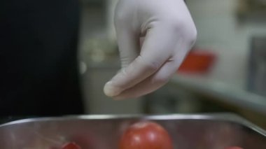 Beyaz eldivenli bir şef, sebzeleri büyük bir konteynırda keserek tuzlar. Yavaş Hareket, Kapat.