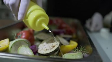 Beyaz eldivenli bir şef bir şişe yağdan ızgara sebze koyar. Ağır çekim, yakın çekim..