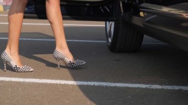 Pahalı bir arabaya binen yüksek topuklu ayakkabılı genç bir kadının ayakları. Yaklaşın, ağır çekim..