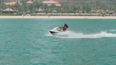 Açık denizlerde jet ski üzerinde can yeleği giymiş esmer bir kadın. Yavaş çekim