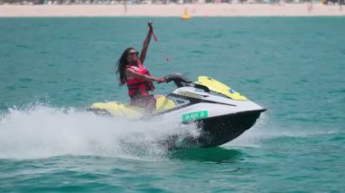 Açık denizlerde jet ski üzerinde can yeleği giymiş esmer bir kadın. Yavaş çekim