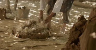 Usta çömlekçi yerde çıplak ayakla kil yoğurur. Gerçek zamanlı, 4k.