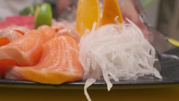 レモンスライス 頭で魚をカットし 黒の正方形のプレート上に赤魚のスライスの異なる種類の寿司の装飾に石灰を置きます — ストック動画
