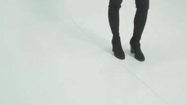 Uzun siyah saçlı, kısa şortlu, beyaz arka planda dans eden esmer bir kadın. Yavaş Hareket, Kapat