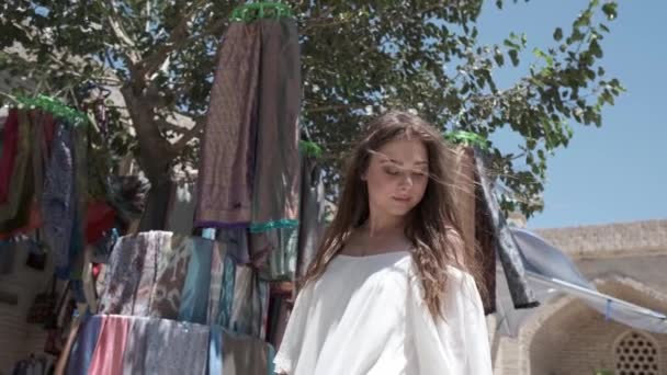 Una Mujer Joven Con Pelo Largo Vestido Ligero Elige Telas — Vídeos de Stock