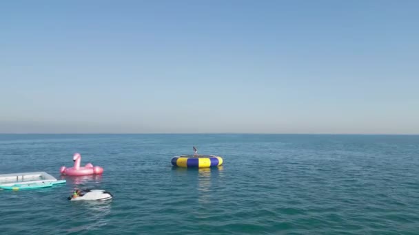ドバイ Uae 2023 無人機は 子供がジャンプするオープン海でインフレータブルトランポリンの周りを飛行します スローモーション 空中ビュー スローモーション — ストック動画