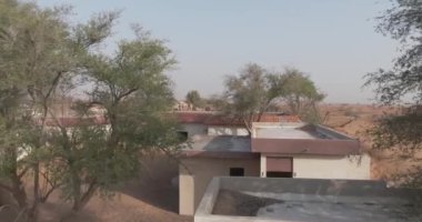 Bir dron Dubai çölünün ortasında kumla kaplı küçük bir kasabada bir deve kervanı yakalıyor. Hava, Yavaş Hareket.