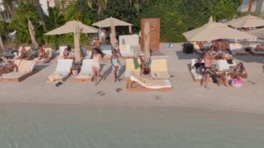 Dubai, BAE - 114 2023: lüks bir otelin plajında bir İHA uçuyor. Mayolu genç kızlar suya giriyor. Hava görünümü.