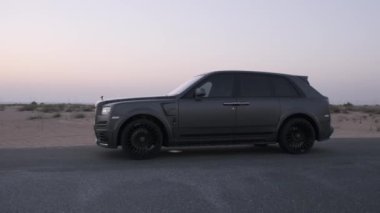 Dubai 'nin kumlu çölünün ortasında, otoyolda gece boyunca farları açık pahalı lüks bir araba duruyor. Yavaş Hareket