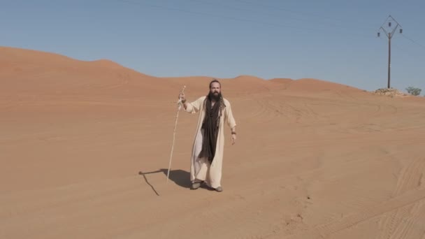 Mladý Muž Bílých Šamanských Šatech Holí Ruce Kráčí Písku Pouště — Stock video