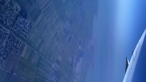 翼とその下の地面の飛行機の窓からの垂直ビデオ 空中風景 — ストック動画
