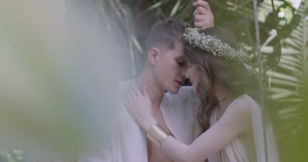 Young Couple Lovers Light White Robes Swing Blooming Spring Garden — Vídeo de stock